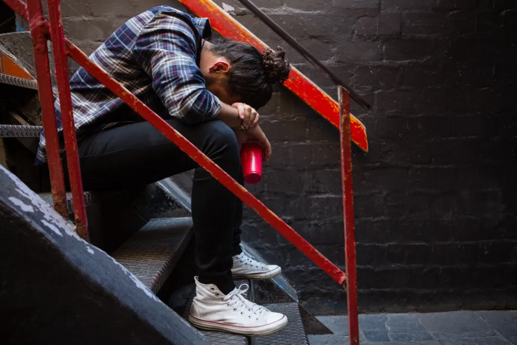 Drunk man sitting on staircase of bar