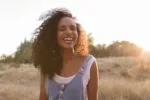 portrait outdoors of a beautiful young afro american woman smiling at sunset. Yellow background. Lifestyle