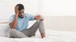 feeling-unwell-hangover-frustrated-young-african-american-man-touching-his-head-holding-glass-of-water-in-bed-copy-space-stockpack-istock