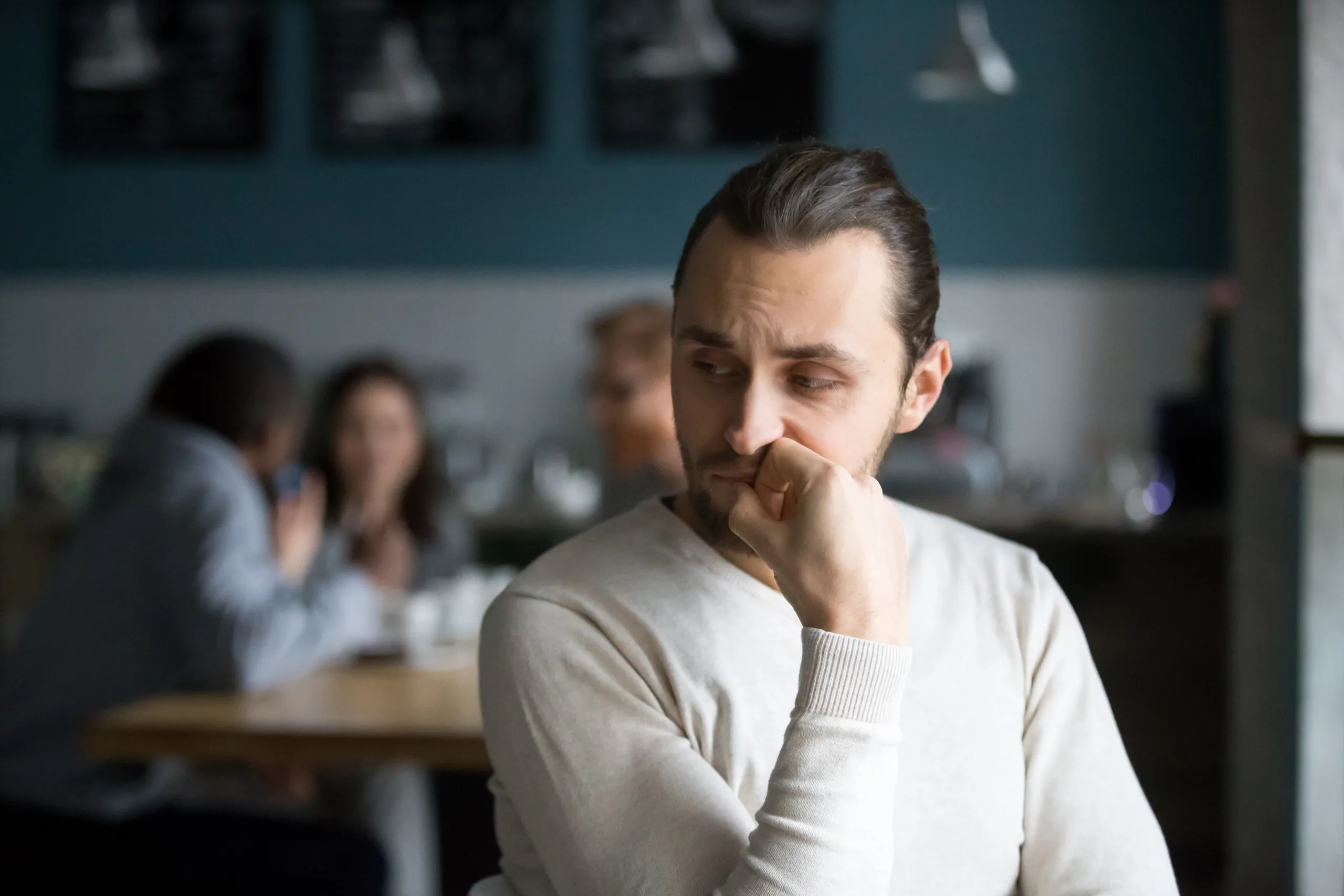 Upset millennial outsider feel offended lack company, young outcast guy suffer from discrimination, jealous of friends hang out together in cafÃ©, envious male loner depressed sit alone in coffeeshop