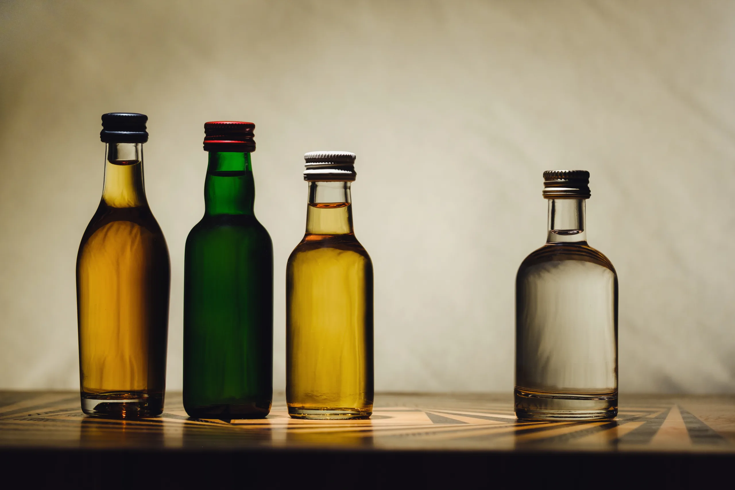 different alcohol bottles are on the table on a light background.