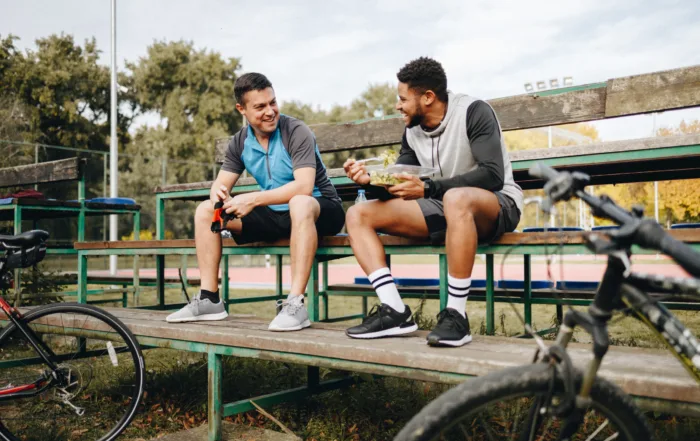 Two young male cyclists taking a break of bicycle ride in the city park talking.
