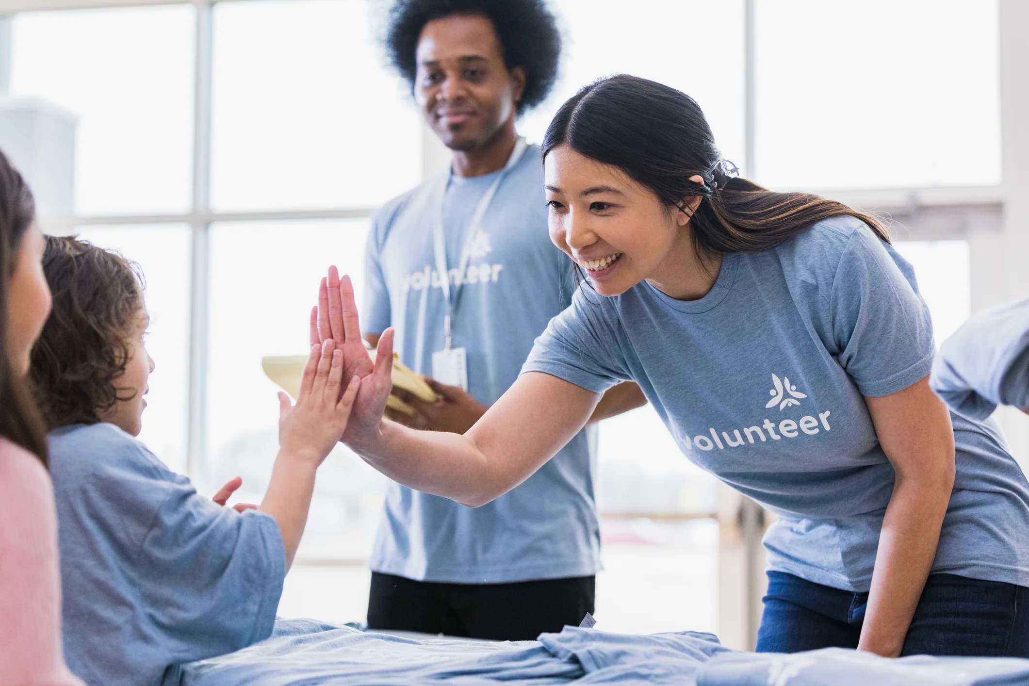 Young adult woman volunteer high fiving a child participating in national prevention week activities