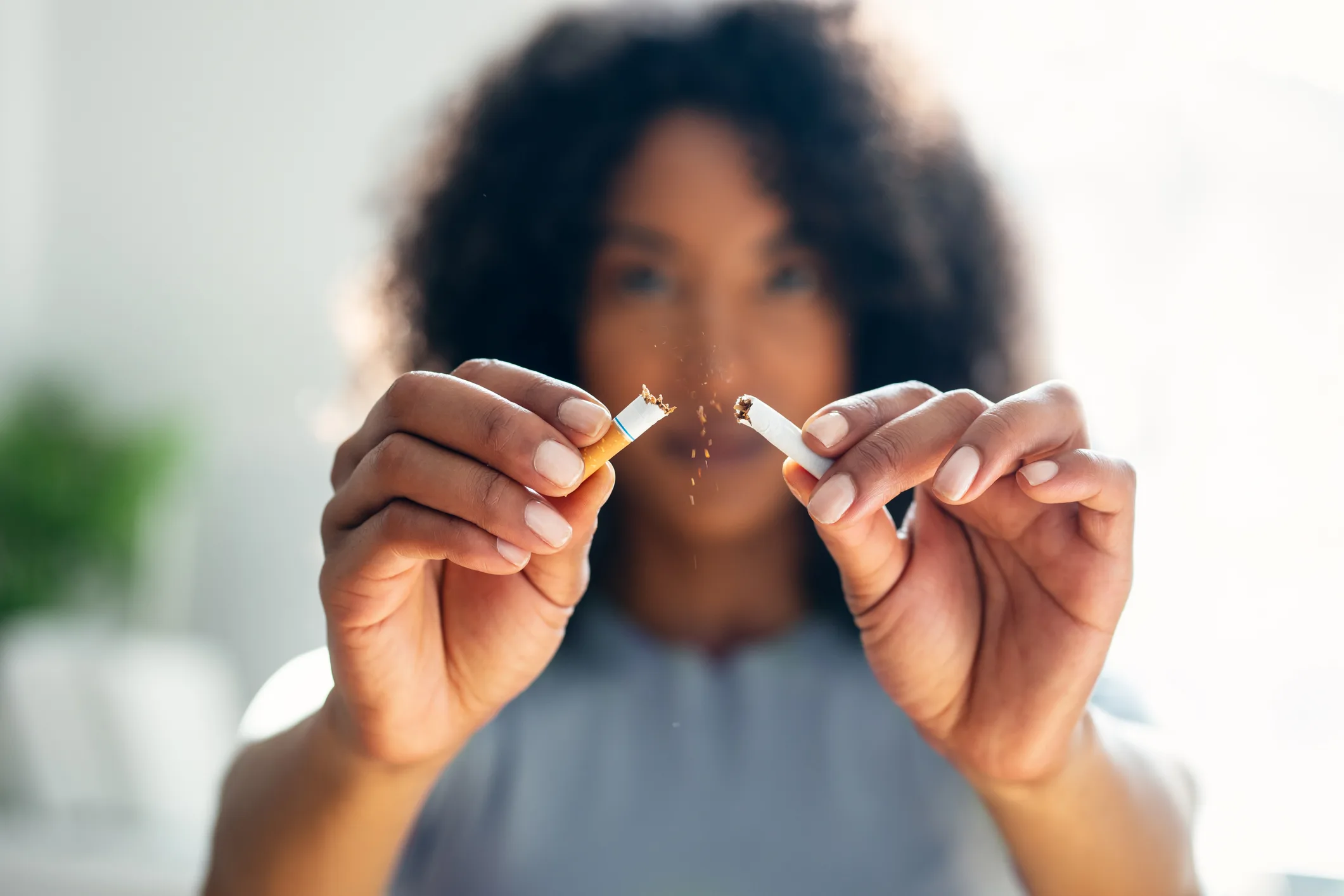 Close up of woman holding cigarette she is breaking in half to signify quitting cold turkey