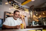 Sad senior man drinking beer on the bar worried cause his heart just started racing