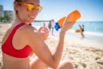 Young woman on beach applying sunscreen to protect from UV rays to take care of herself as part of recovery