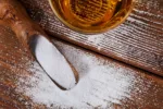 Powdered alcohol dumped onto a table next to a glass filled with alcohol