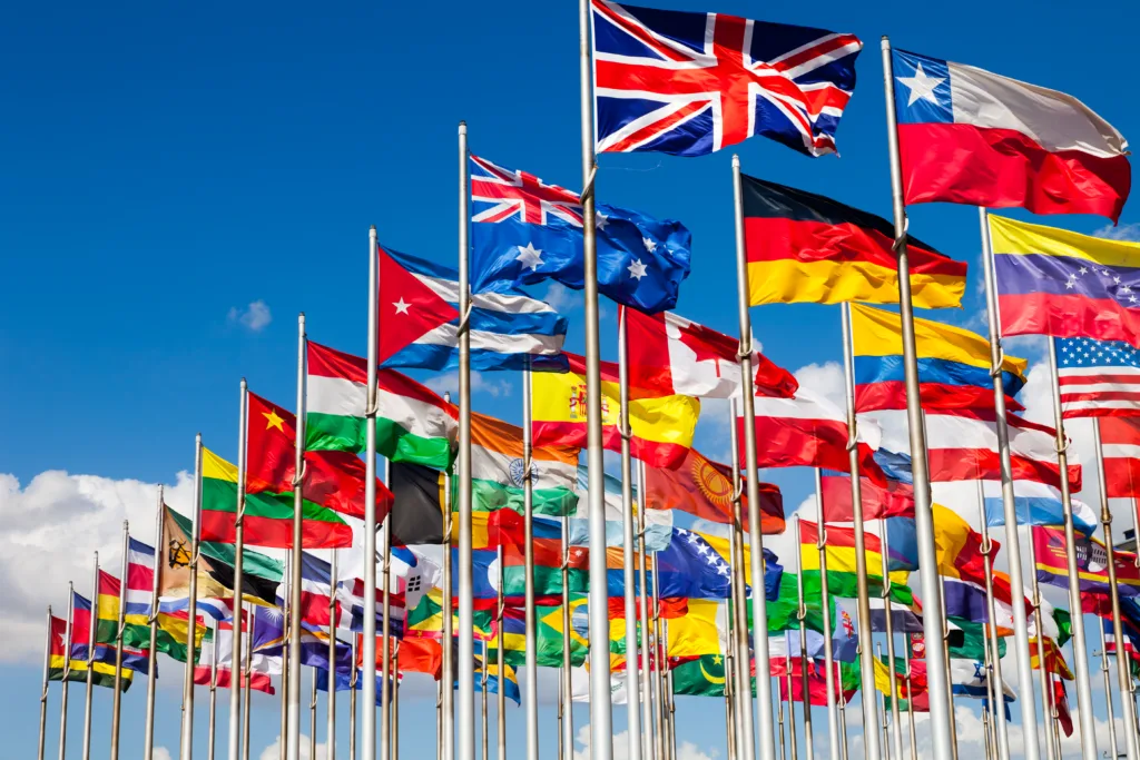 Group of flags of many different nations against blue sky