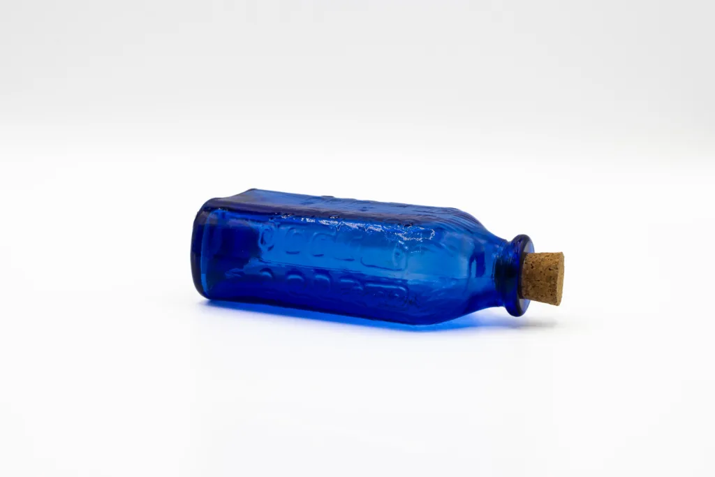 blue glass bottle with cork laying on its side with Feel Free energy drink inside