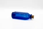 blue glass bottle with cork laying on its side with Feel Free energy drink inside