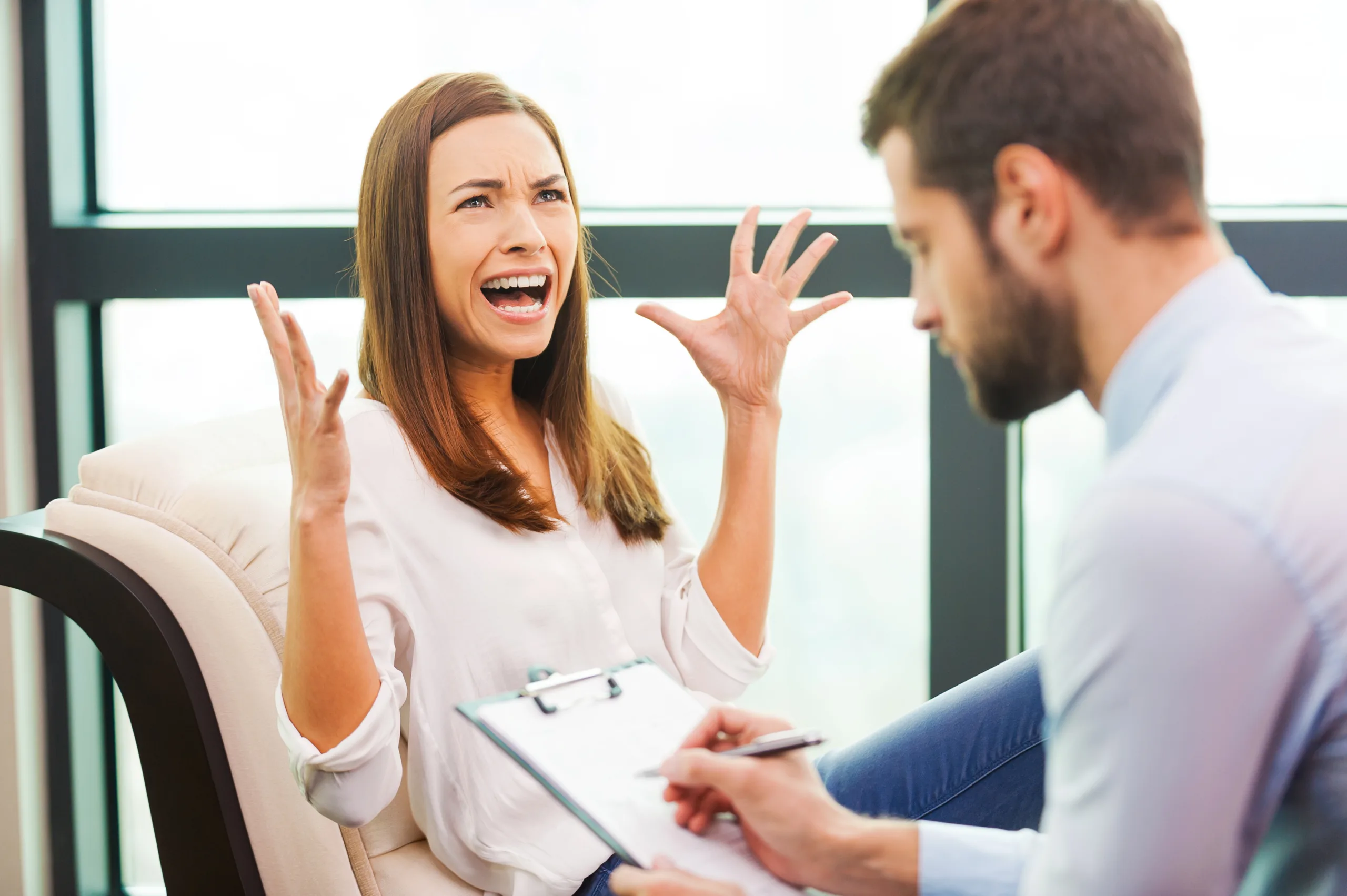 young woman sitting in chair with therapist for rational emotional behavior therapy
