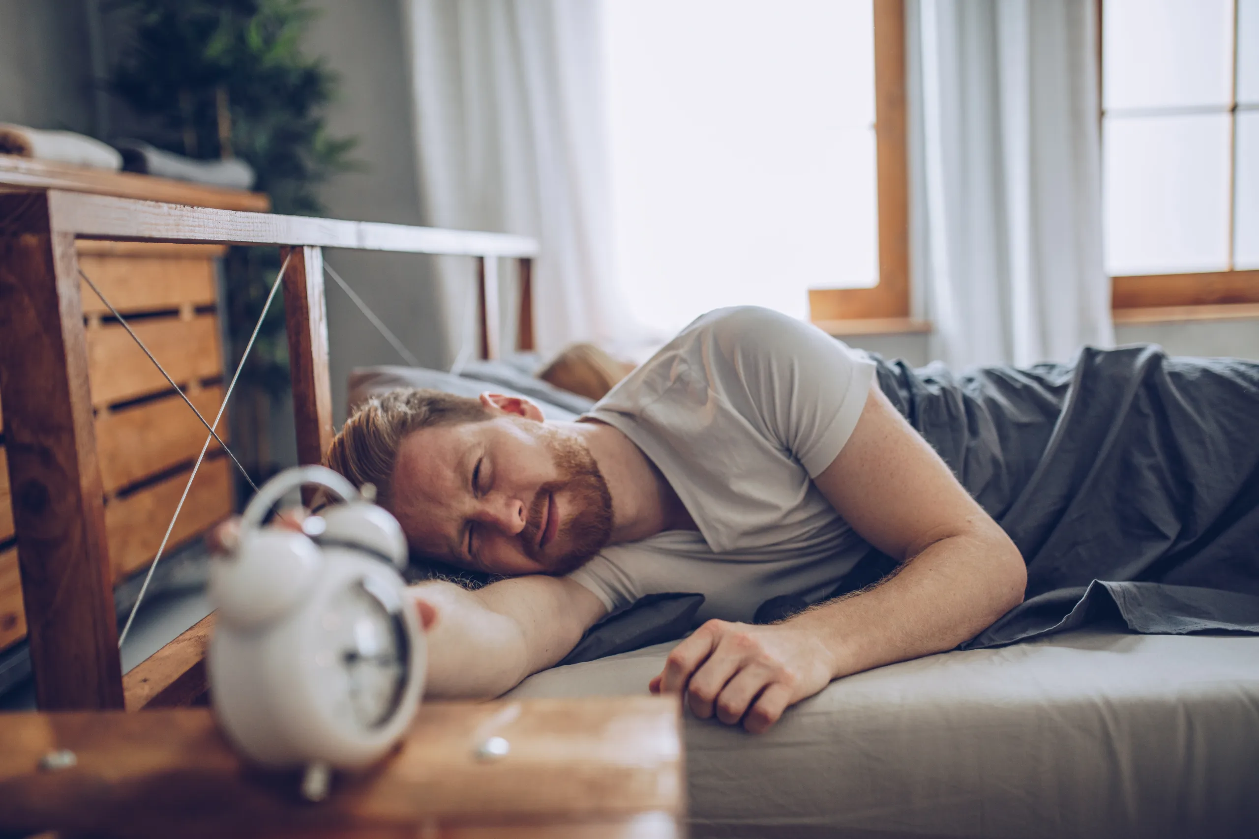 lying in bed, ginger man getting up early, mad with the clock.