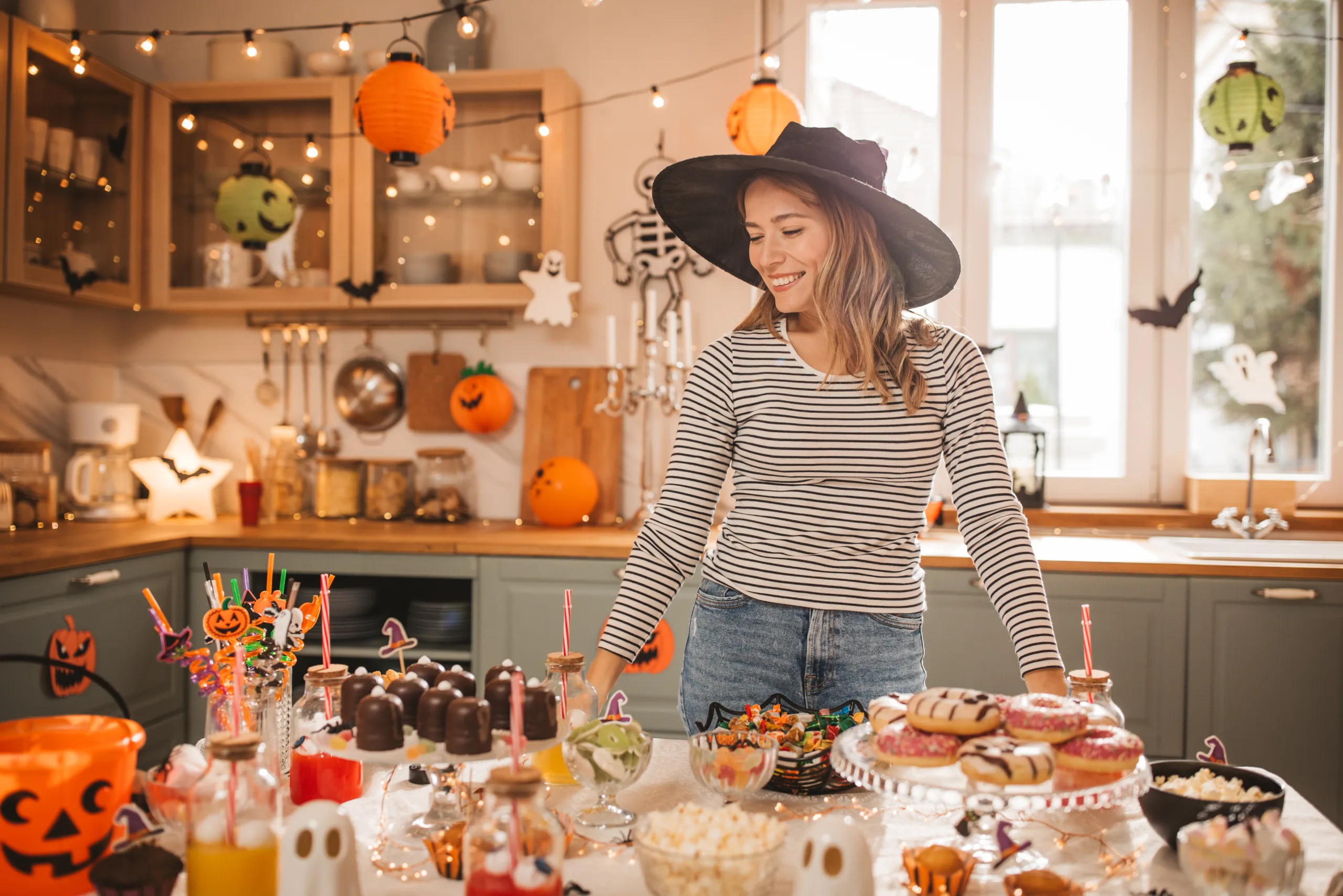 Young woman in costume setting sweet table for Halloween lunch.